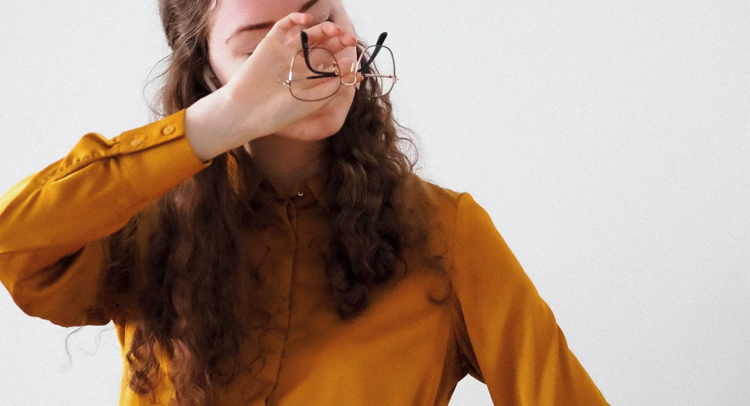 Woman with glasses covering eyes with hand